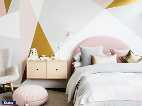 Geometric Gold Feature Wall with Chair and pink cushion with grey carpet and pink and grey pillows
